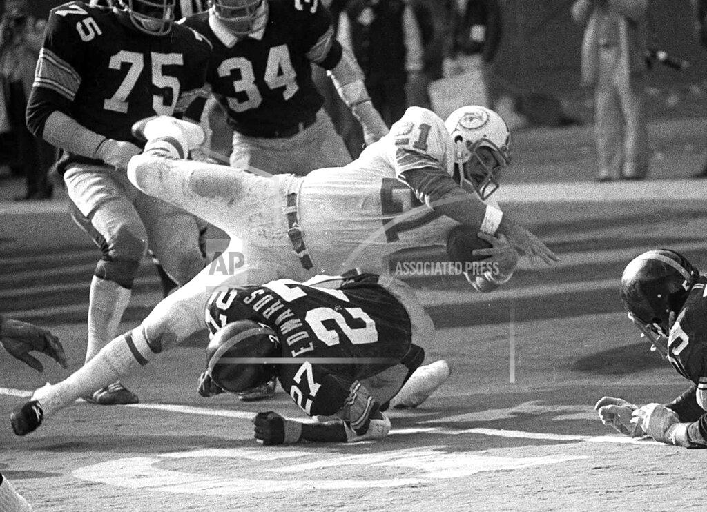 Uncredited FILE - In this Dec. 31, 1972, file photo, Miami Dolphins Jim Kiick goes headfirst over Pittsburgh Steelers" Glen Edwards as Kiick scores in third quarter of the AFC championship game at Pittsburgh's Three Rivers Stadium. Former running back Kiick, who helped the Dolphins achieve the NFL’s only perfect season in 1972, has died at age 73. In recent years Kiick battled memory issues and lived in an assisted living home, and the team announced his death Saturday, June 20, 2020. (AP Photo, File)