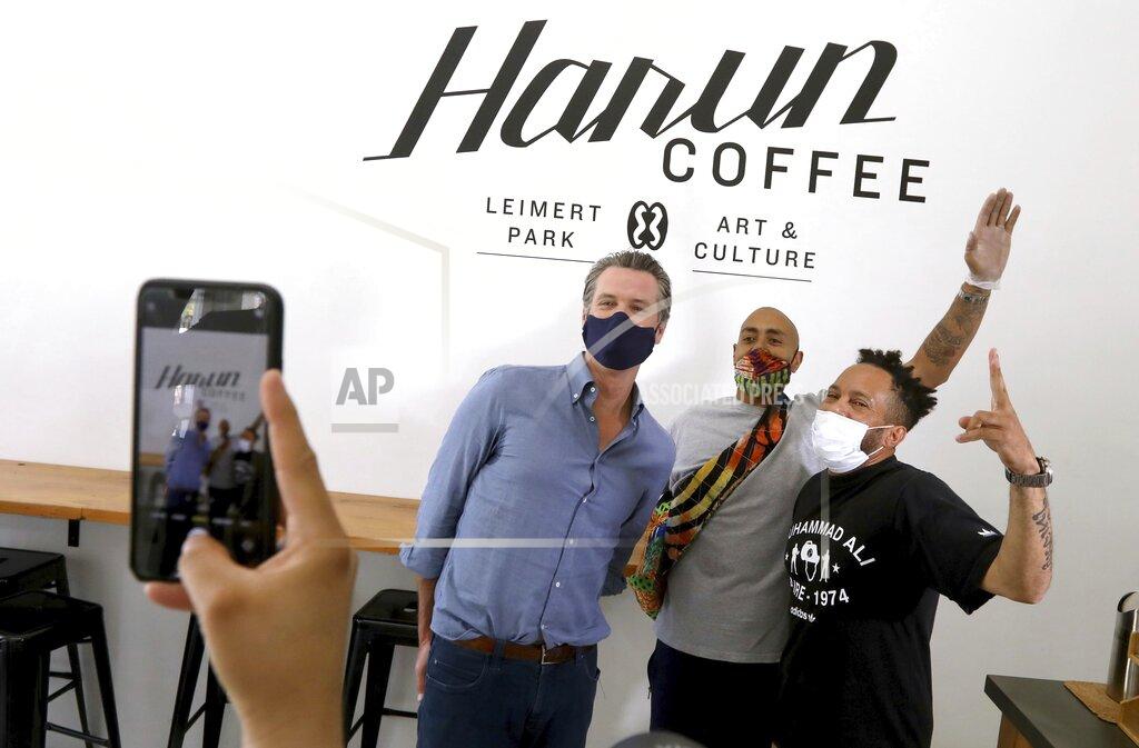 Genaro Molina California Gov. Gavin Newsom, from left, has his picture taken with Harun Johnson, owner of Harun Coffee, and employee Anthony Thorne while the governor visited businesses in Leimert Park in Los Angeles on Wednesday, June 3, 2020. (Genaro Molina/Los Angeles Times via AP, Pool)