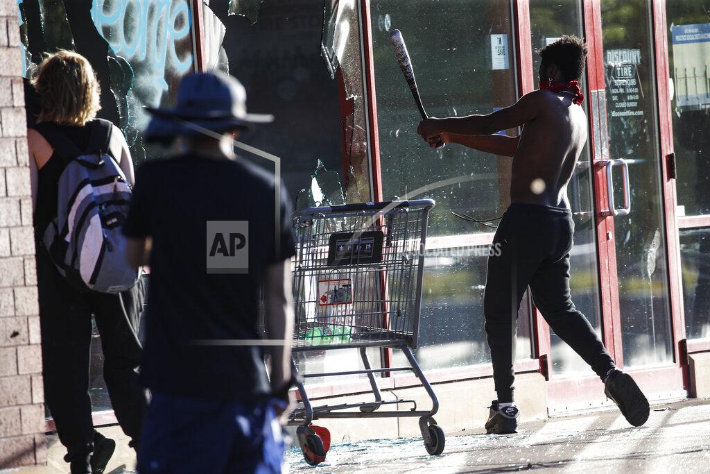 John Minchillo FILE - In this May 28, 2020 file photo, a protestor breaks a window of a business with a baseball bat, in St. Paul, Minn. The destruction caused by vandals and looters in cities across the country, who struck as demonstrators took to the streets in reaction to the killing of George Floyd in Minneapolis, has devastated small businesses already reeling from the coronavirus outbreak. (AP Photo/John Minchillo, File)
