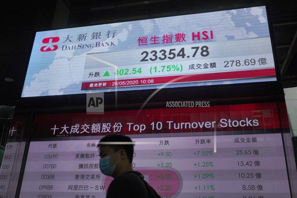 A man wearing face mask walks past a bank electronic board showing the Hong Kong share index at Hong Kong Stock Exchange Tuesday, May 26, 2020. Asian shares are rising as some regions in Japan resume near-normal business activity, with hopes for economic recovery overshadowing worries over the coronavirus pandemic. (AP Photo/Vincent Yu)