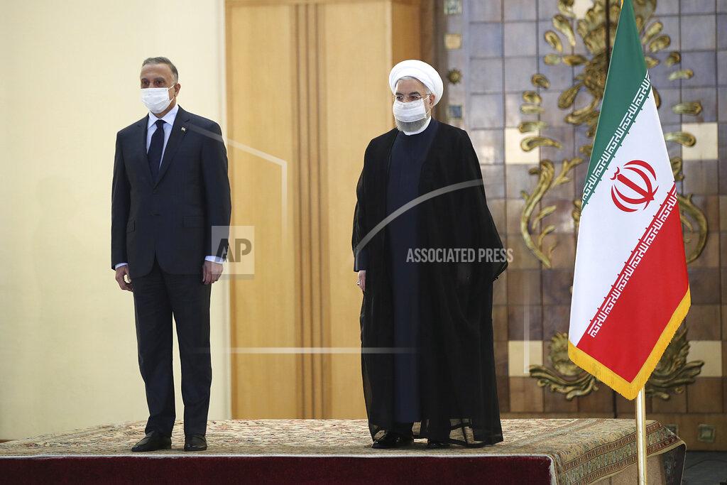Uncredited In this photo released by the official website of the office of the Iranian Presidency, President Hassan Rouhani, right, welcomes Iraqi Prime Minister Mustafa al-Kadhimi as they wear protective face masks to help prevent spread of the coronavirus, during an official arrival ceremony, in Tehran, Iran, Tuesday, July 21, 2020. (Iranian Presidency Office via AP)