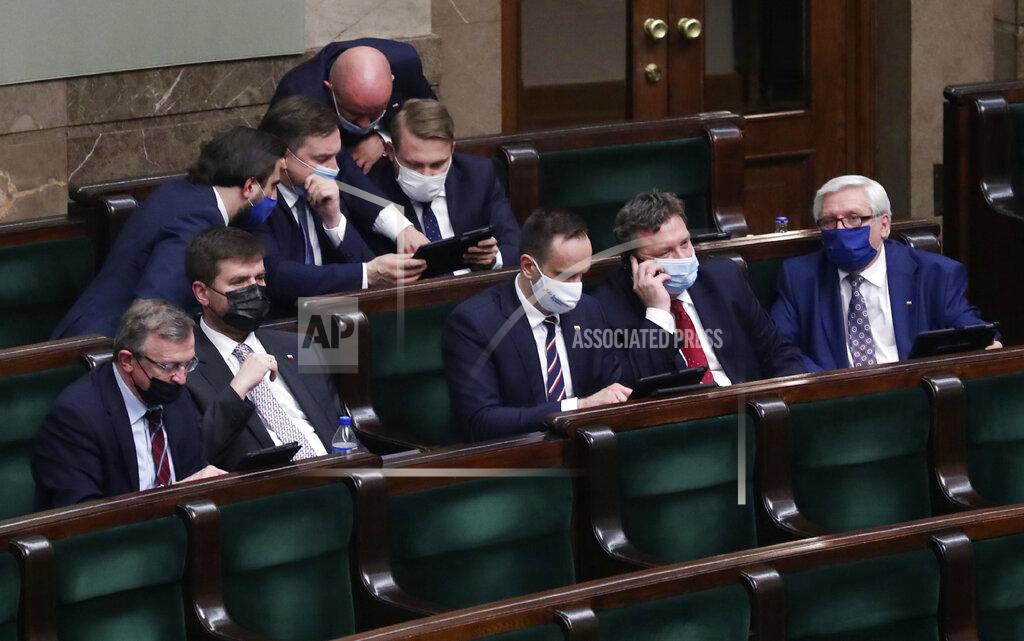 Czarek Sokolowski Poland's Justice Minister Zbigniew Ziobro, center, with tablet, and members of his small Solidarity Poland party that is a partner in the ruling right-wing coalition, after a crucial vote in parliament, in Warsaw, Poland, on Tuesday, May 4, 2021. Polish lawmakers have voted to approve the nation’s spending plan for the 58 billion euros ($70 billion) it expects to receive from the European Union’s pandemic recovery plan. (AP Photo/Czarek Sokolowski)