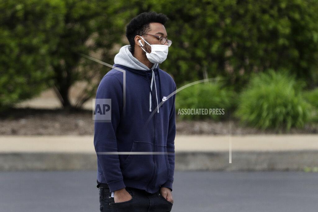 A man wears a protective mask as walks in a parking lot Monday, April 13, 2020, in St. Louis where parts of the city have been hit much harder than others by the coronavirus outbreak. Of people who are known to have died from from COVID-19 in St. Louis, blacks are dying at a much higher rate than other populations. (AP Photo/Jeff Roberson)