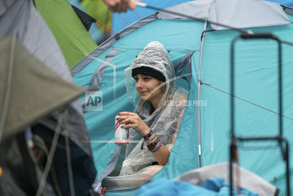 Joe Giddens A festivalgoers shelters from the rain on the first day of Download Festival at Donington Park at Castle Donington, England, Friday June 18, 2021. The three-day music and arts festival is being held as a test event to examine how Covid-19 transmission takes place in crowds, with the the capacity significantly reduced from the normal numbers. (Joe Giddens/PA via AP)
