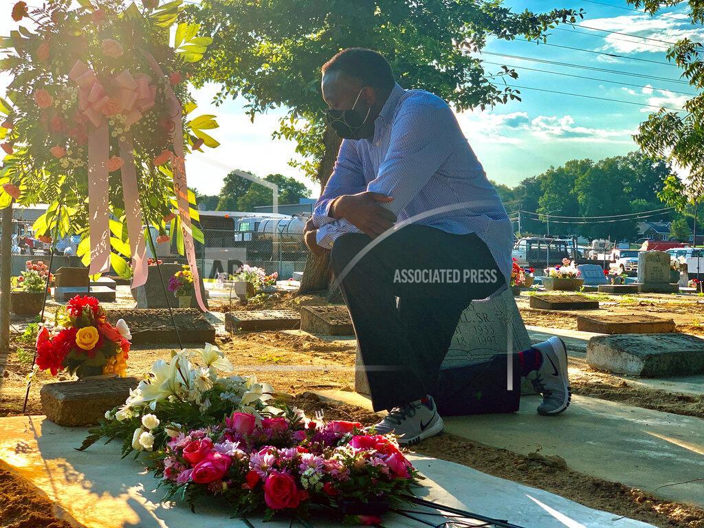 Kim Chandler Will Boyd kneels at the grave of a family member who died after contracting the coronavirus, Saturday, June 20, 2020, in Montgomery, Ala. He says his family has lost multiple family members to COVID-19. (AP Photo/Kim Chandler)