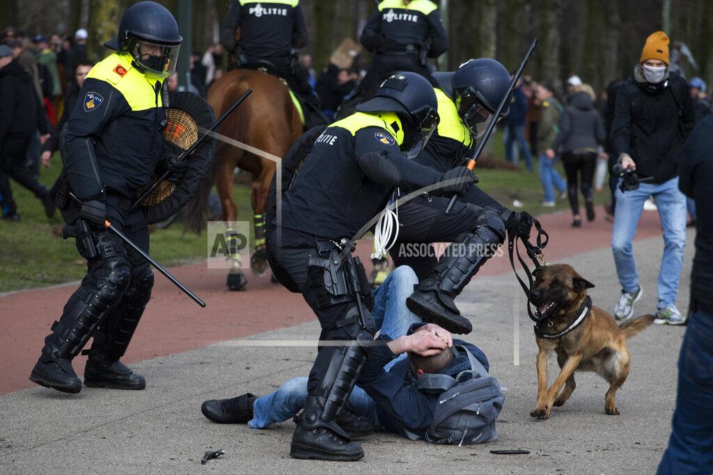Peter Dejong Dutch riot police kick a man during a demonstration to protest government policies including the curfew, lockdown and coronavirus related restrictions in The Hague, Netherlands, Sunday, March 14, 2021. Thousands of people took part in the rally ahead of three days of voting starting Monday in a general election. (AP Photo/Peter Dejong)
