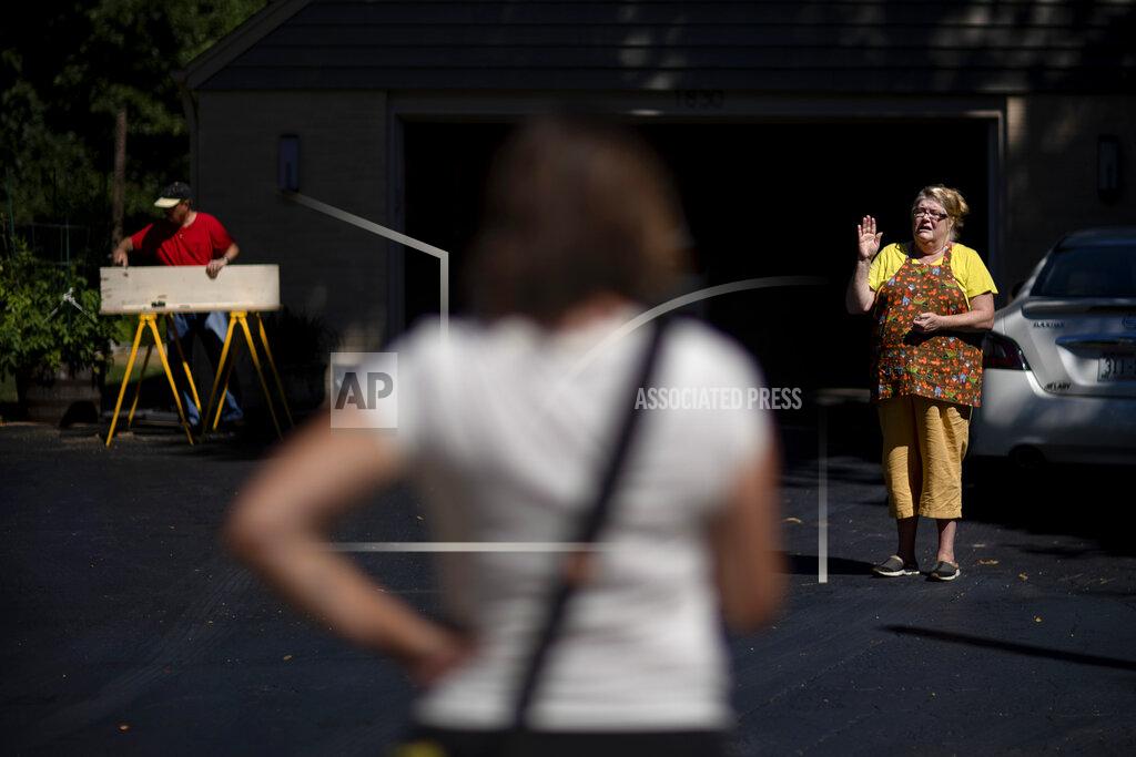 David Goldman Lee Snodgrass, center, chair of the local Democratic party who is also running for a seat in the state legislature, talks with Candice Meyer, right, outside her home as Snodgrass knocks on doors campaigning Aug. 18, 2020, in Appleton, Wis. Snodgrass walked through a neighborhood that leans for President Donald Trump. She could recite facts about the economy and the pandemic, several millions jobs lost, a rising body count and Republicans, like Meyer, would defend Trump. (AP Photo/David Goldman)