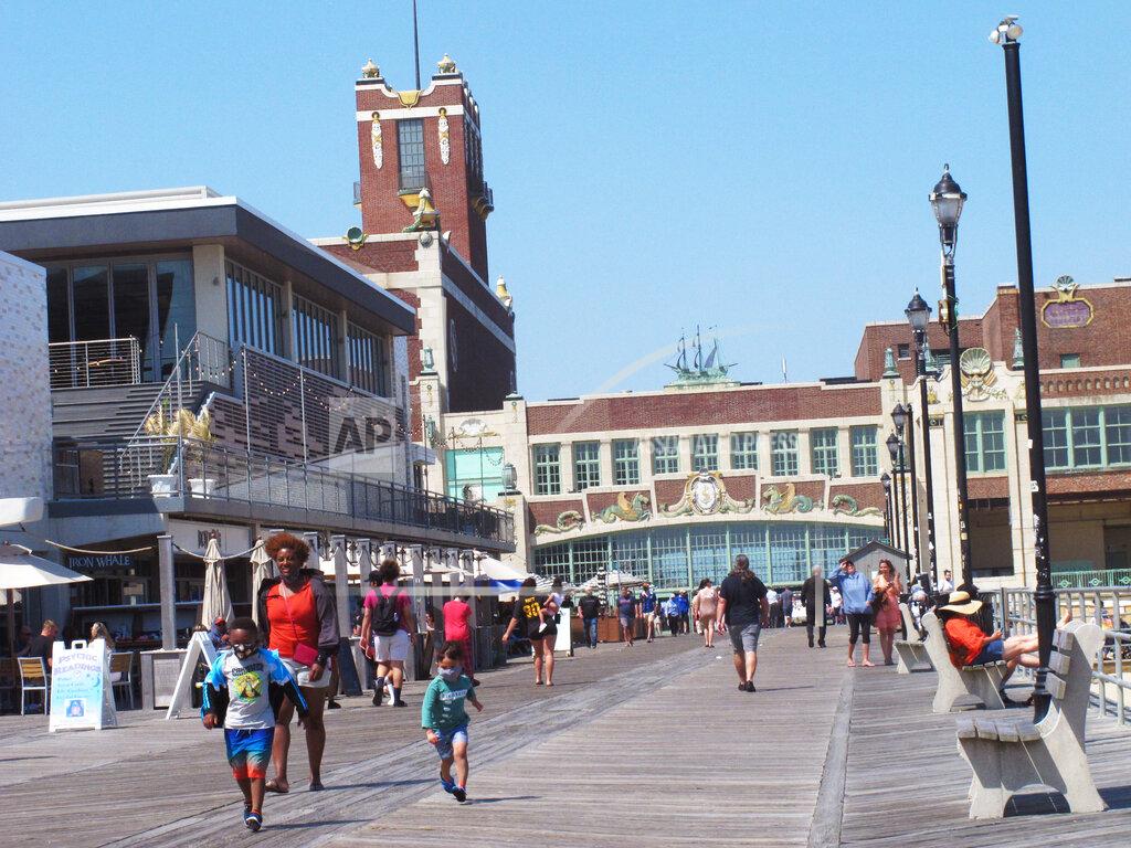 Wayne Parry A woman walks with two children on the boardwalk in Asbury Park N.J. on Friday, May 21, 2021. Businesses and residents alike expect this summer at the Jersey Shore to be busier than last year as more people get vaccinated and COVID19 restrictions are scaled back or eliminated. (AP Photo/Wayne Parry)