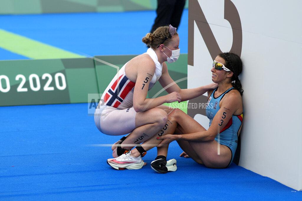David Goldman Claire Michel, of Belgium, is assisted by Lotte Miller of Norway after the finish of the women's individual triathlon competition at the 2020 Summer Olympics, in Tokyo, Japan, July 27, 2021. (AP Photo/David Goldman)