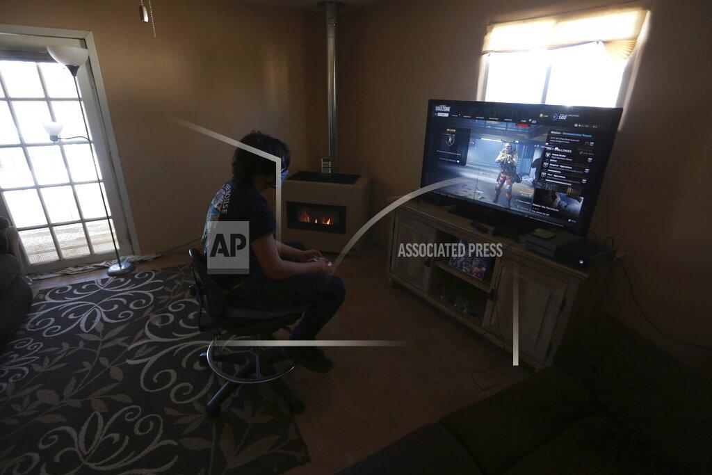 Cedar Attanasio Javin Lujan Lopez, 17, a senior at Pojoaque High School, plays video games at his house on Monday, Feb. 22, 2021, in Española, N.M. He isn’t sure what will happen after graduation. He's considering a welding certificate program at the local community college. He applied to universities in New Mexico and Colorado but feels like the pandemic year didn’t allow him to put his best foot forward. (AP Photo/Cedar Attanasio)