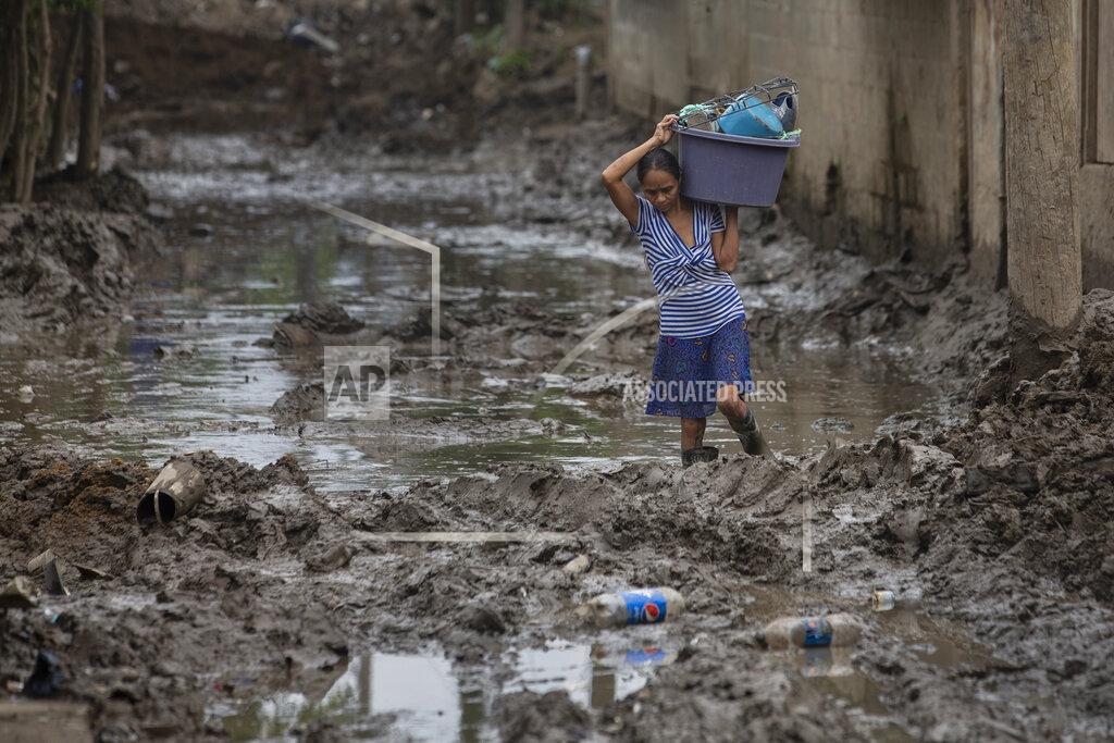 Moises Castillo A resident continues to extract items from her home after it was flooded by last year's hurricanes Eta and Iota in the Saviñon Cruz neighborhood of San Pedro Sula, Honduras, Tuesday, Jan. 12, 2021. The devastation wrought by November's hurricanes and the economic damage of the COVID-19 pandemic has added to the forces of poverty and gang violence that drive Hondurans to migrate. (AP Photo/Moises Castillo)