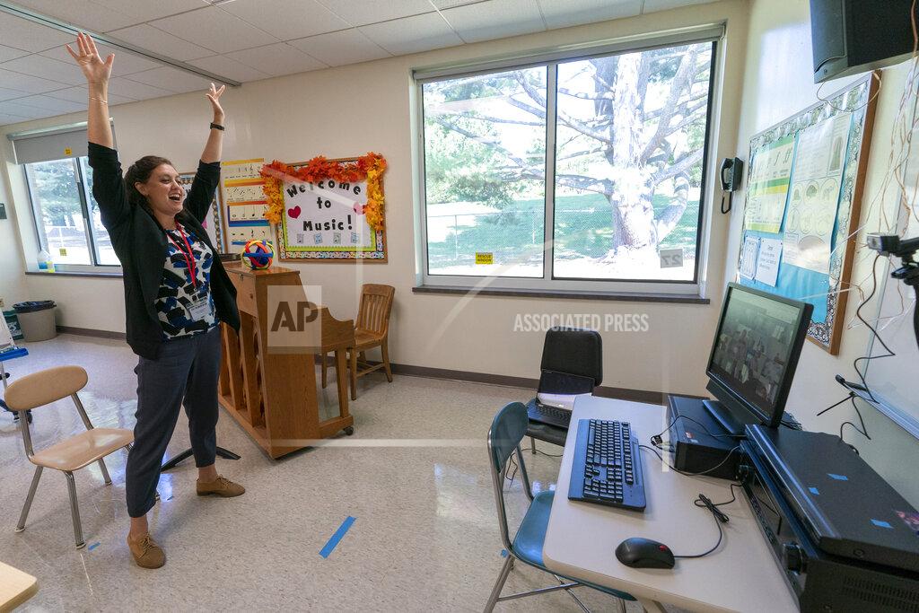 FILE - In this Oct. 6, 2020, file photo, Christine Free teaches a remote music class during the coronavirus outbreak at the Osborn School in Rye, N.Y. President Joe Biden says he wants most schools serving kindergarten through eighth grade to reopen by late April 2021. But even if that happens, many schools in urban areas that serve high concentrations of minority students are likely to stay closed. (AP Photo/Mary Altaffer, File)