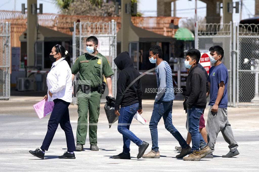 Julio Cortez Migrants, who were caught trying to sneak into the United States, are led by a U.S. Customs and Border Protection agent, second from left, at the McAllen-Hidalgo International Bridge while being deported to Reynosa, Mexico, Thursday, March 18, 2021, in Hidalgo, Texas. A surge of migrants on the Southwest border has the Biden administration on the defensive. The head of Homeland Security acknowledged the severity of the problem Tuesday but insisted it's under control and said he won't revive a Trump-era practice of immediately expelling teens and children. (AP Photo/Julio Cortez)