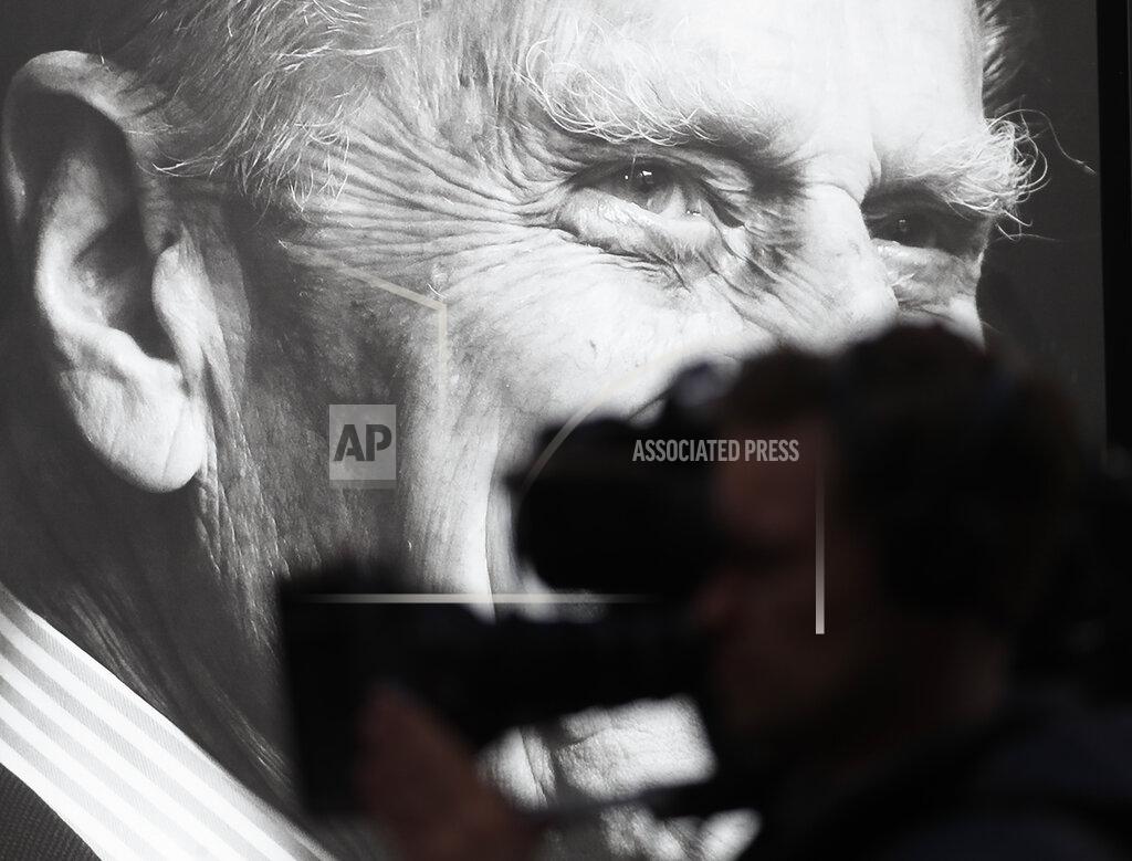 Alastair Grant A TV camera is silhouetted against a portrait of Prince Philip in Windsor, England, Friday, April 16, 2021. Prince Philip husband of Britain's Queen Elizabeth II died April 9, aged 99, his funeral will take place Saturday at Windsor Castle in St George's Chapel. (AP Photo/Alastair Grant)