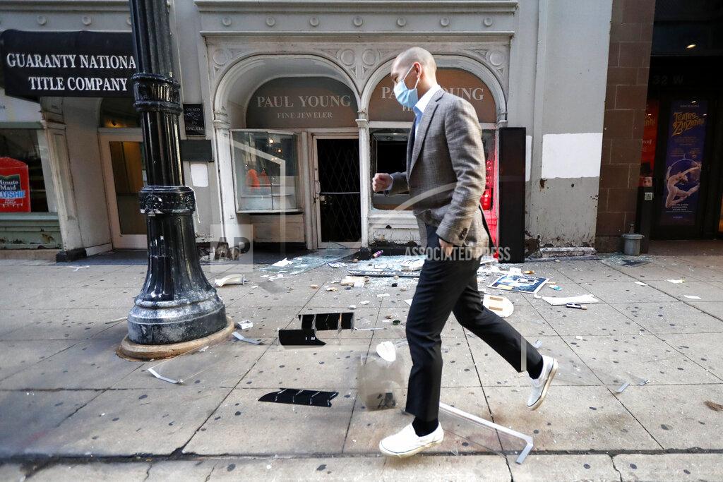 Charles Rex Arbogast FILE In this Monday, Aug. 10, 2020, file photo, a pedestrian hops over debris after a jewelry store was vandalized in Chicago's famed Loop. A Chicago police task force that was formed after crowds swarmed into downtown and smashed their way into hundreds of stores in August is still investigating and making arrests four months later. (AP Photo/Charles Rex Arbogast, File)