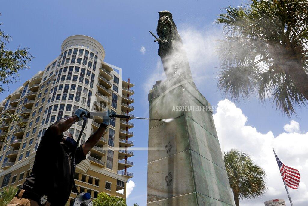 Ivy Ceballo A Hillsborough County employee with the Rapid Response Team removes remaining graffiti on the pedestal of the statue at Columbus Statue Park in Tampa on Tuesday, June 30, 2020. A column of black fists lined the sides of pedestal. (Ivy Ceballo/Tampa Bay Times via AP)