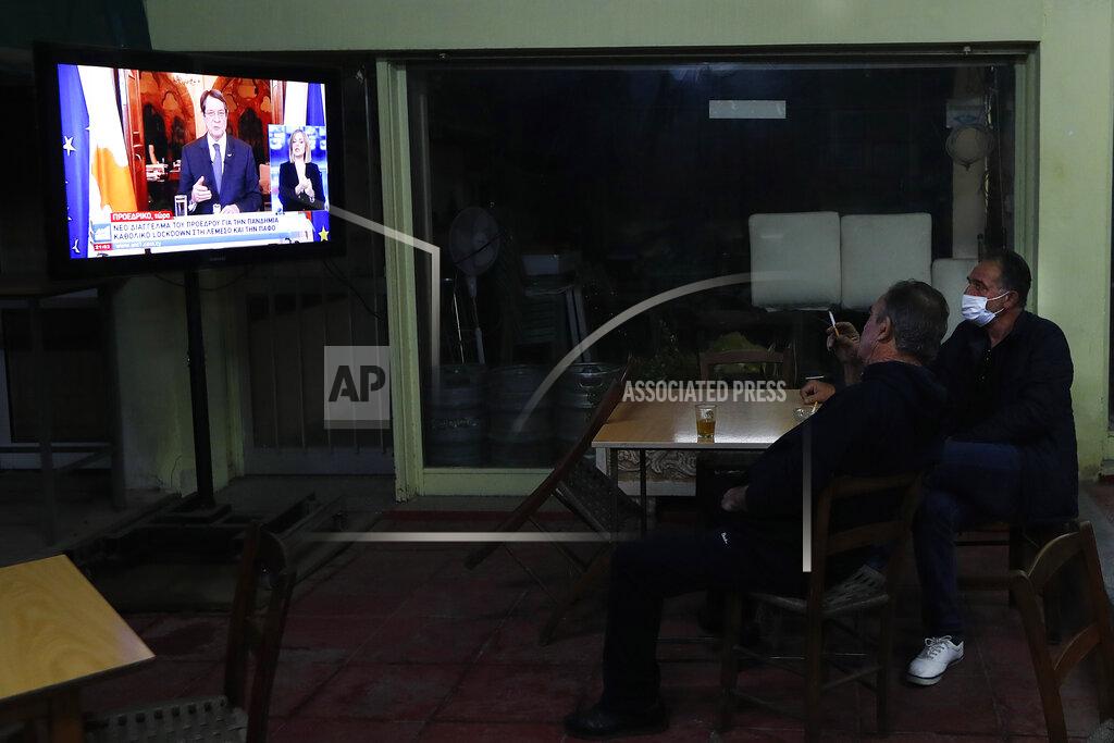 Petros Karadjias Two men sit at a social club and watch the televised address of Cypriot President Nicos Anastasiades explaining the need for additional restrictions to beat back a surge in COVID-19 cases in Nicosia suburb of Lakatamia, Cyprus, on Tuesday, Nov. 11, 2020. Cyprus has put its entire southwest under a strict 19-day lockdown, banning any non-essential movement of people and shuttering bars and restaurants after a string of escalating restrictions failed to curb a sharp increase in COVID-19 infections. (AP Photo/Petros Karadjias)