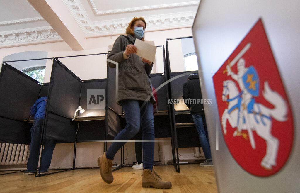 Mindaugas Kulbis A woman, wearing face masks to protect against coronavirus walks to cast their ballots at a polling station during parliamentary elections in Vilnius, Lithuania, Sunday, Oct.11, 2020. Polls opened Sunday for the first round of national election in Lithuania, where voters will renew the 141-seat parliament and the ruling four-party coalition is widely expected to face a stiff challenge from the opposition to remain in office. (AP Photo/Mindaugas Kulbis)