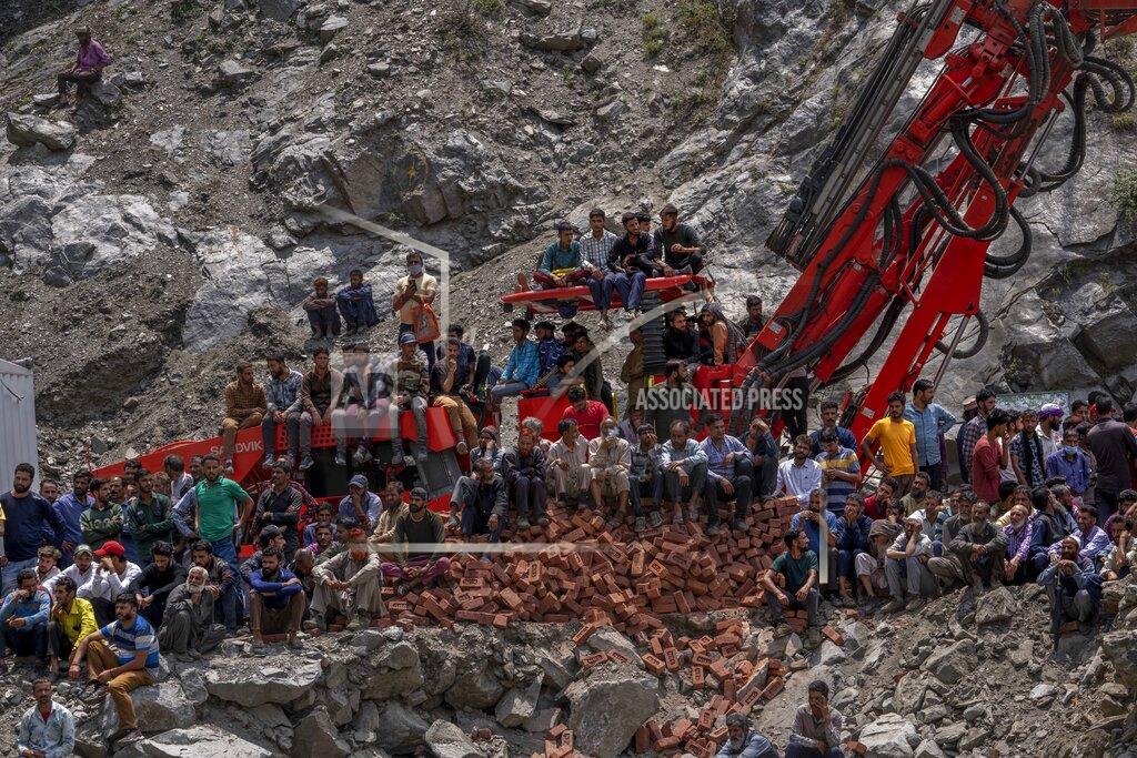 Dar Yasin Villagers watch from a distance as earth movers dig through rubble of a collapsed tunnel in Ramban district, south of Srinagar, Indian controlled Kashmir, Friday, May 20, 2022. An official in Indian-controlled Kashmir said Friday that 10 workers were trapped after part of a road tunnel collapsed in the Himalayan region. (AP Photo/Dar Yasin)