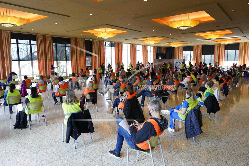 Ted S. Warren Wearing colored vests, volunteer workers sit socially distanced as they take part in a training session before a shift working at a mass vaccination clinic at Seattle University, Friday, Feb. 26, 2021, in Seattle. As states ramp up vaccination distribution in the fight against the coronavirus, volunteers are needed to do everything from direct traffic to check people in to keep vaccination sites running smoothly. In return for their work, they're often given a shot — including those who are young and healthy and may not have otherwise been able to receive the shot until later in the year. (AP Photo/Ted S. Warren)