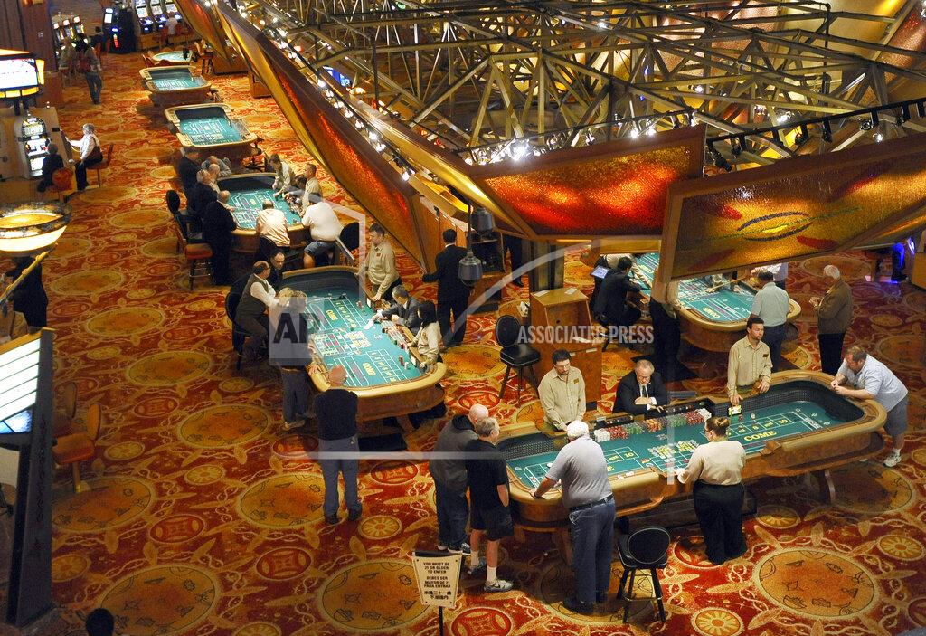 FILE - In this Sept. 18, 2013 file photo, patrons play craps at tables at Mohegan Sun in Uncasville, Conn. The shutdown of the Mohegan Sun and Foxwoods casinos for the pandemic has contributed to soaring unemployment in eastern Connecticut, a region that has seen some of the biggest spikes in jobless numbers despite relatively few infections. (AP Photo/Jessica Hill, File)