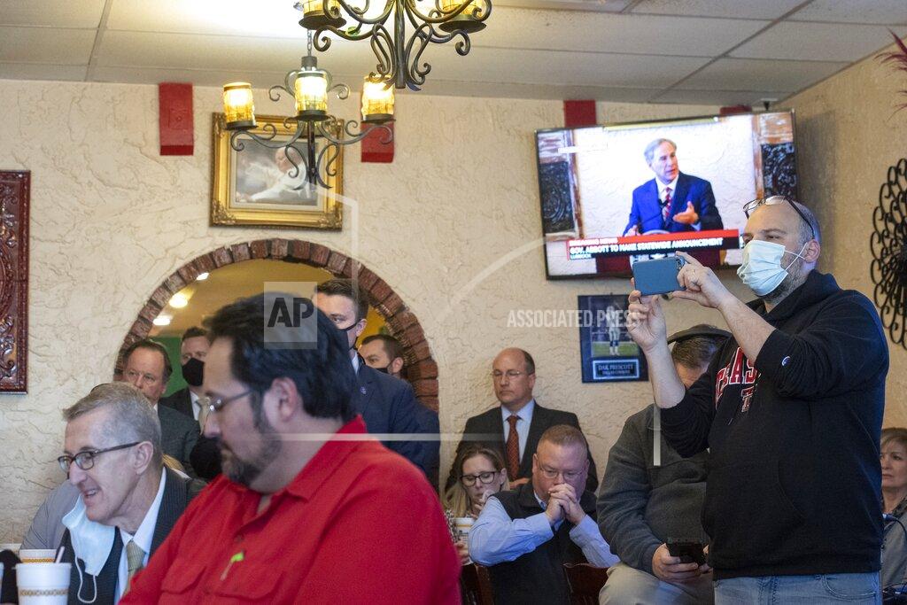Justin Rex Texas Gov. Greg Abbott delivers an announcement, broadcasted on the TV in the background, as a crowd watches him make it at Montelongo's Mexican Restaurant on Tuesday, March 2, 2021, in Lubbock, Texas. Governor Abbott announced that he is rescinding executive orders that limit capacities for businesses and the statewide mask mandate. (Justin Rex/Lubbock Avalanche-Journal via AP)
