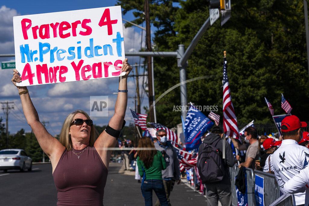 Manuel Balce Ceneta Karen Simon from the District of Columbia, let, waves a banner together with other supporters of President Donald Trump, gathered outside the Walter Reed National Military Medical Center in Bethesda, Md., Monday, Oct. 5, 2020. Trump said Monday he's leaving the military hospital where he has been treated for COVID-19 and will continue his recovery at the White House. (AP Photo/Manuel Balce Ceneta)
