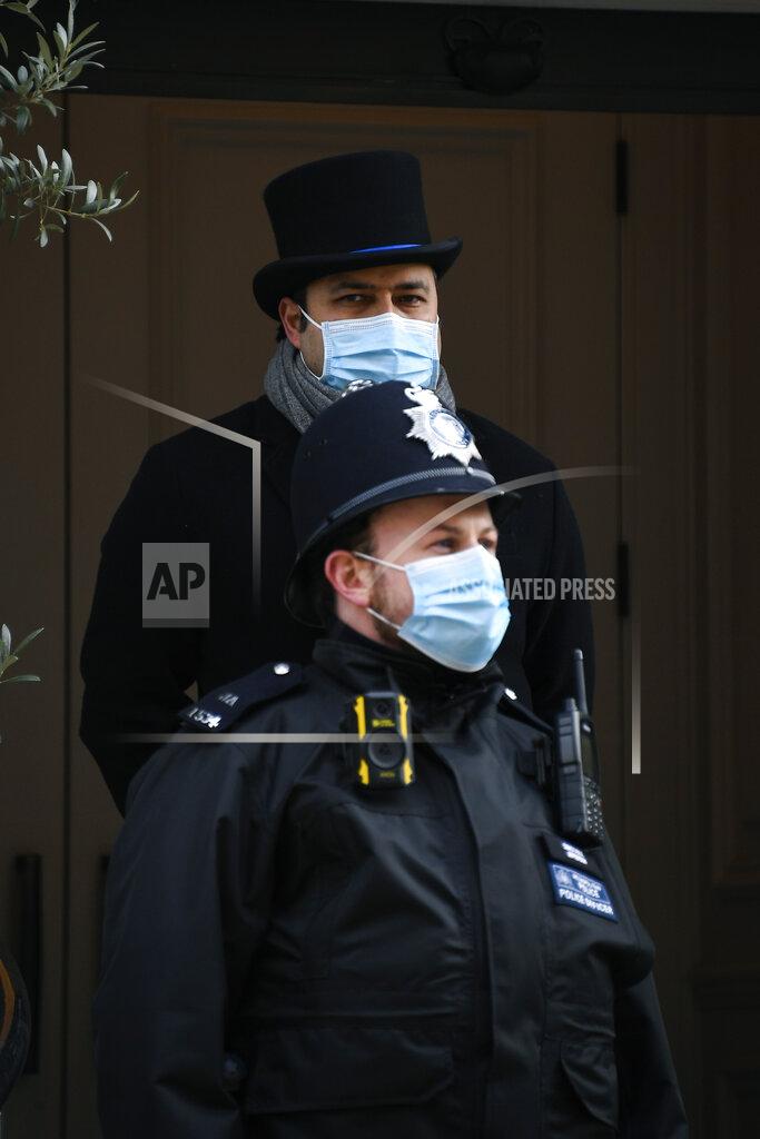 Alberto Pezzali A doorman and a police officer stand guard at the main entrance of the King Edward VII Hospital where Britain's Prince Philip is receiving treatment as a police van stands guard, in London, Sunday, March 14, 2021. The 99-year-old husband of Queen Elizabeth II remains hospitalized after a heart procedure. (AP Photo/Alberto Pezzali)