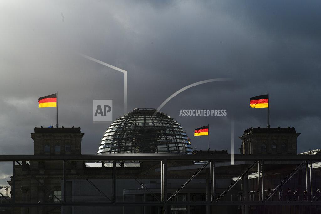 Markus Schreiber FILE - In this Friday, Nov. 29, 2019 file photo, German national flags catch the sun on top of the German parliament building, the Reichstag building in Berlin, Germany. German voters elect a new parliament on Sunday, Sept. 26, 2021, a vote that will determine who succeeds Chancellor Angela Merkel after her 16 years in power. (Photo/Markus Schreiber, File)
