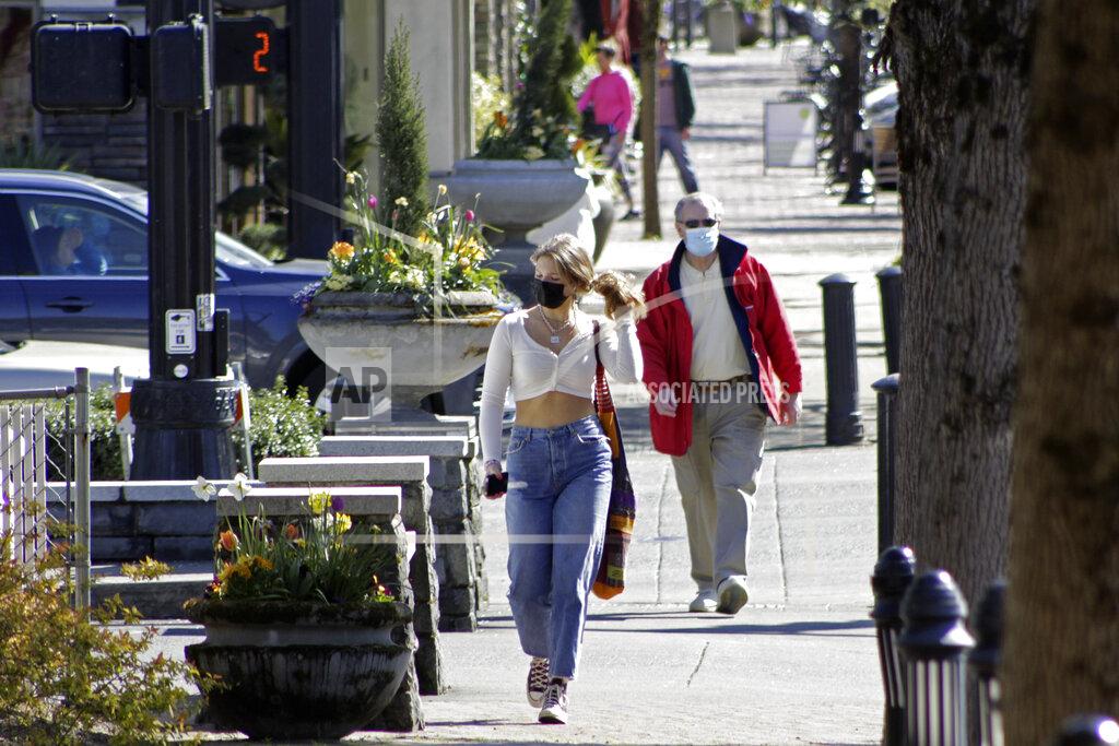 Gillian Flaccus Residents wearing masks walk in downtown Lake Oswego, Ore., on Sunday, April 11, 2021. Tens of thousands of Oregon residents are angry about a proposal to make permanent an emergency rule that requires masks and social distancing in the state's businesses and schools to prevent the spread of COVID-19. Opponents worry about government overreach and fear that state officials won't remove the mask requirements for businesses even after threat of the virus has receded if the emergency rule becomes permanent. (AP Photo/Gillian Flaccus)