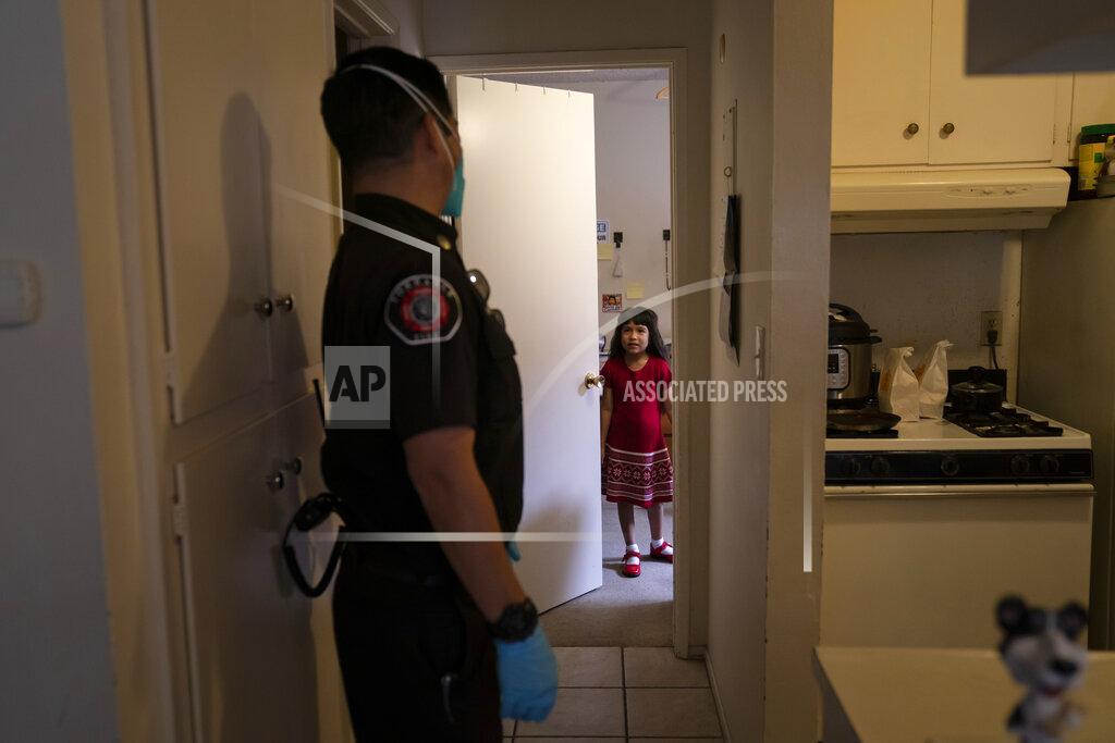 Jae C. Hong Maria Franco, 7, talks with Torrance fire Capt. John Kubota while her two aunts, who have muscular dystrophy, are monitored after receiving the Pfizer COVID-19 vaccine in their apartment, Wednesday, May 12, 2021, in Torrance, Calif. Teamed up with the Torrance Fire Department, Torrance Memorial Medical Center started inoculating people at home in March, identifying people through a city hotline, county health department, senior centers and doctor's offices, said Mei Tsai, the pharmacist who coordinates the program. (AP Photo/Jae C. Hong)