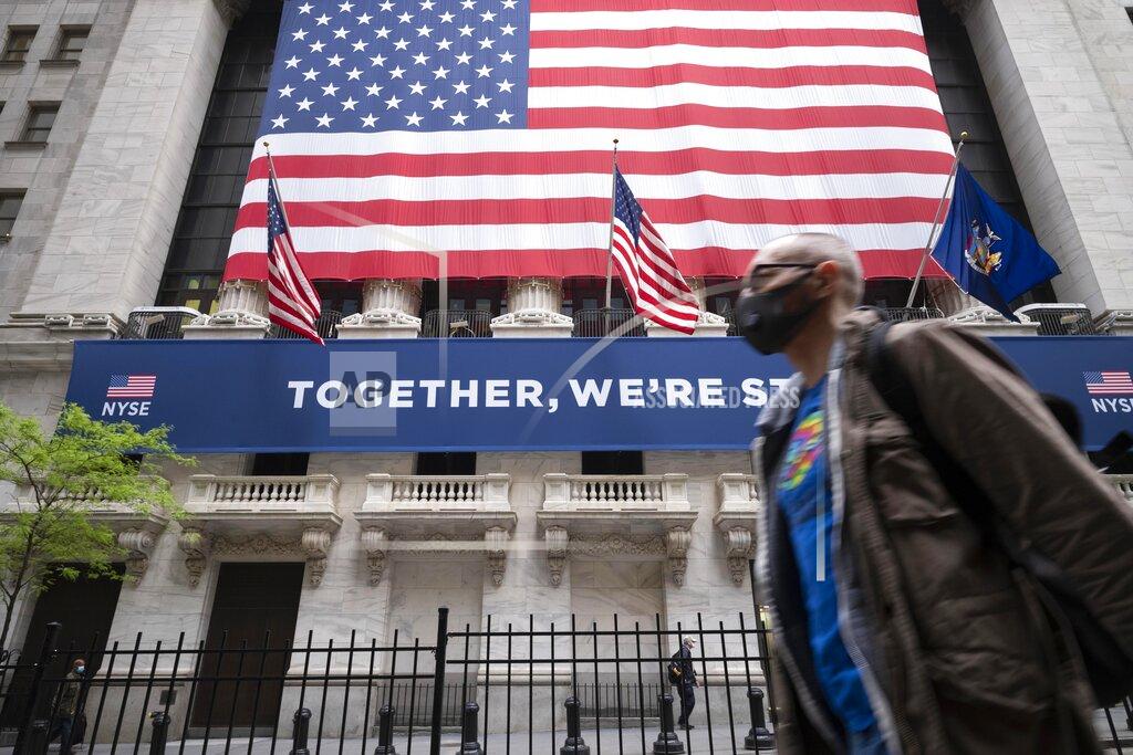 FILE - In this May 26, 2020, file photo, a man wearing a protective face mask passes the New York Stock Exchange, as employees arrive for the partial reopening of the trading floor. Stocks are climbing in early trading on Monday, Aug. 24 on Wall Street, adding to their record-breaking run from last week. The S&P 500 was up 0.7% after the first 25 minutes of trading, following up on solid gains for stock markets across much of Europe and Asia. (AP Photo/Mark Lennihan, File)