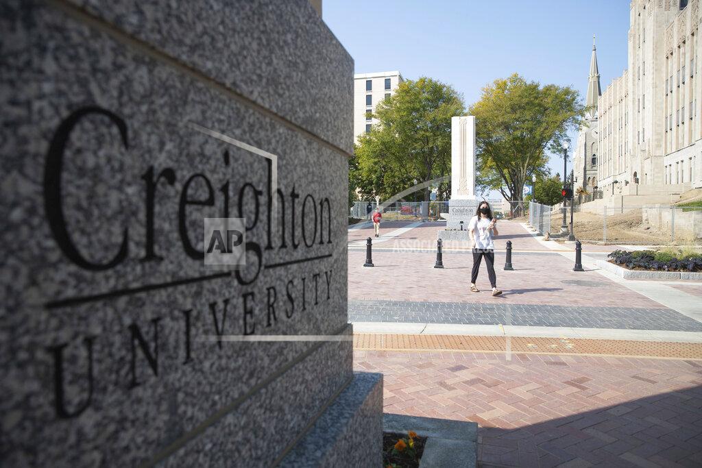 Lily Smith FILE - Students walk across 24th Street after the 24th Street dedication and ribbon cutting on the Creighton University campus in Omaha, Neb. on Thursday, Sept. 24, 2020. Colleges across the country are struggling to salvage the fall semester as campus coronavirus cases skyrocket and tensions with local health leaders flare. Schools have locked down dorms, imposed mask mandates, barred student fans from football games and toggled between online and in-person classes. (Lily Smith/Omaha World-Herald via AP)