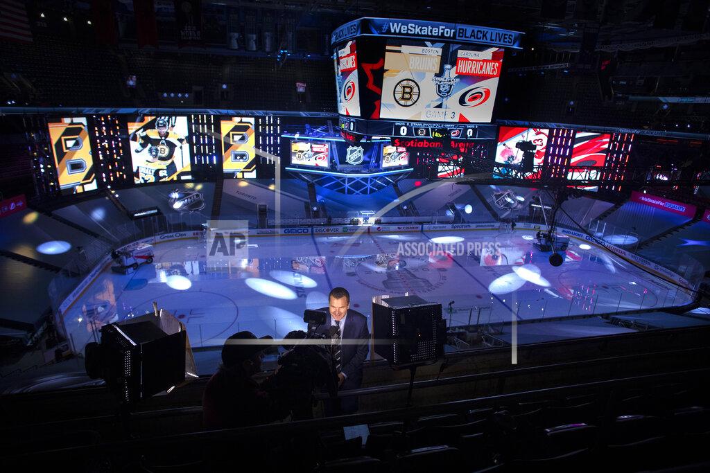 Chris Young A television presenter does a pre-game report as specially constructed displays are illuminated ahead of a NHL first round Stanley Cup playoff game between the Carolina Hurricanes and Boston Bruins, in Toronto, on Saturday, Aug. 15, 2020. (Chris Young/The Canadian Press via AP)