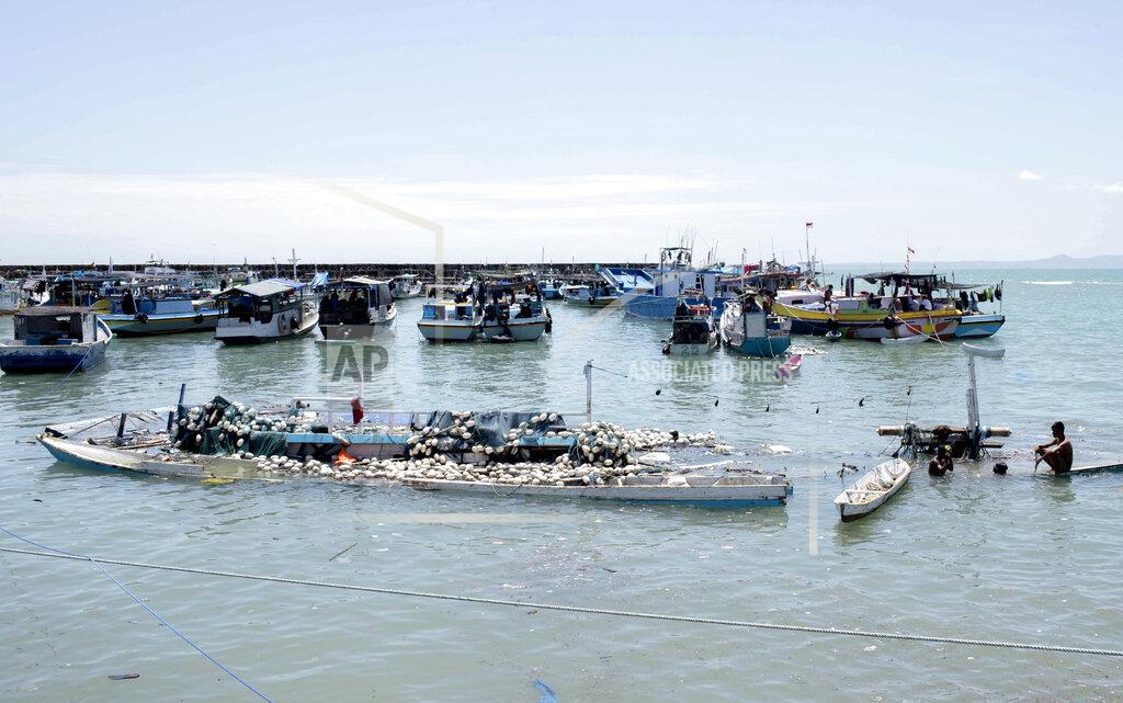 Armin Septiexan Men look for salvageable items amid floating debris and damaged boats following a storm at a port in Kupang, East Nusa Tenggara province, Indonesia, Wednesday, April 7, 2021. Multiple disasters caused by severe weather in eastern Indonesia and neighboring East Timor have left a number of people dead or missing. (AP Photo/Armin Septiexan)