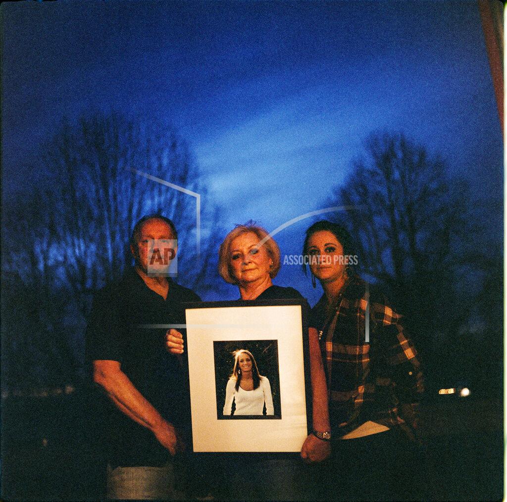 David Goldman In this photo made with a medium format film camera, Jeff and Lola Carter stand with their daughter, Amanda, and a framed photo of Kayla, their daughter who struggled with drug addiction, Thursday, March 18, 2021, at their home in Milton, W.Va., Kayla Carter grew up in a tiny town 20 miles from Huntington, in a house with a swimming pool in the backyard. She had a brilliant mind for math and loved the stars. Her family always thought she'd grow up to work for NASA. Instead, she was addicted to opioids by the time she turned 20. "We went through living hell," said Lola. Kayla was hospitalized in June with endocarditis, a heart infection common among injection drug users. It seemed like she was suddenly determined to live. In October, her mother couldn't reach her one Friday. She went to her apartment, and found her dead on her bathroom floor. They are still waiting for the medical examiner's report, but her father would rather never see it. It brings him comfort to think she died from a complication from her surgeries, and not that she relapsed and overdosed. Either way, the drugs killed her, he said. "The only thing about any of it gives me any relief at all," he says, "is knowing we're not the only ones." (AP Photo/David Goldman)