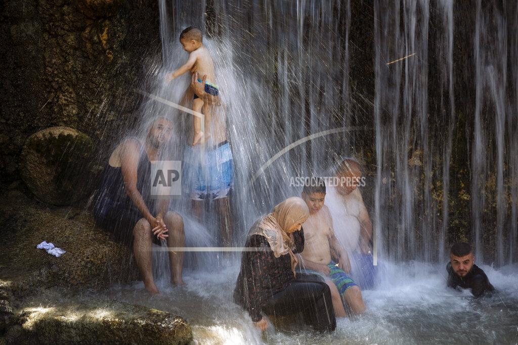 Oded Balilty Israeli Arabs stand under a waterfall during the Muslim Eid al-Adha holiday at the Gan HaShlosha national park near the northern Israeli town of Beit Shean, Wednesday, July 21, 2021. Eid al-Adha meaning "Feast of Sacrifice," this most important Islamic holiday marks the willingness of the Prophet Ibrahim (Abraham to Christians and Jews) to sacrifice his son. (AP Photo/Oded Balilty)
