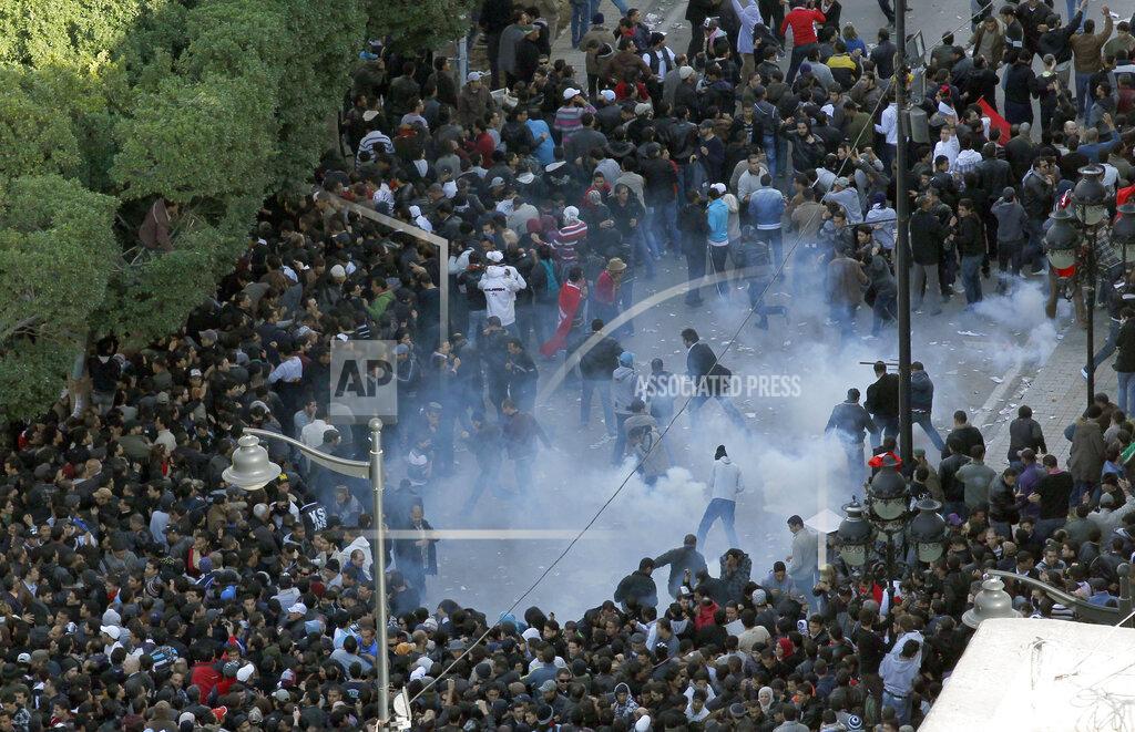 Christophe Ena FILE - In this file photo dated Friday, Jan. 14, 2011, demonstrators scatter after police officers use teargas during a protest in Tunis. Tunisia's official news agency says President Zine El Abidine Ben Ali has declared a state of emergency as riots escalated in his North African nation. On Thursday Jan. 14, 2021, Tunisia commemorates 10 years since the flight into exile of its iron-fisted leader, Zine El Abidine Ben Ali, pushed from power in a popular revolt that foreshadowed the so-called Arab Spring. (AP Photo/Christophe Ena, FILE)
