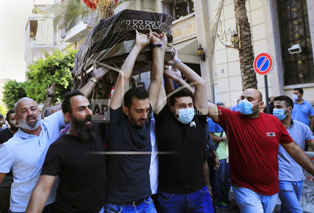 Hussein Malla Mourners carry the coffin of Ibrahim Harb, 35, who was critically injured in the massive explosion at Beirut's port last year and who died on Monday nearly 14 months after the blast, in Beirut, Lebanon, Tuesday, Sept. 28, 2021. On Aug. 4, 2020, hundreds of tons of ammonium nitrate, a highly explosive material used in fertilizers, ignited after a massive fire at the port. The death brings to at least 215 the number of people who have been killed by the blast, according to official records. (AP Photo/Hussein Malla)