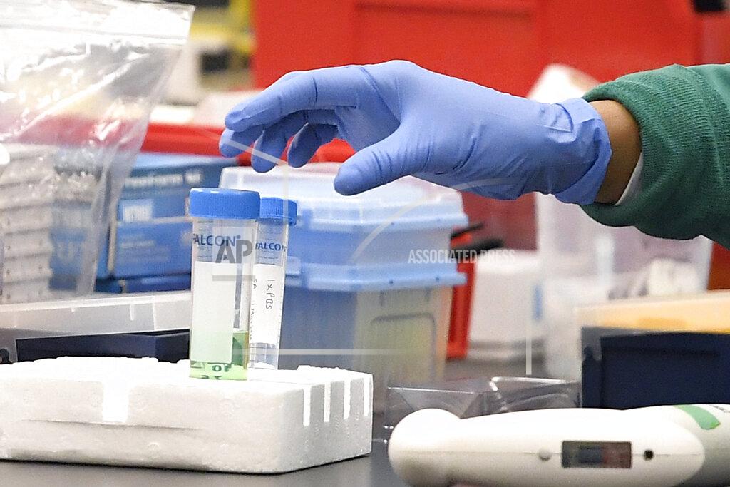 Jessica Hill FILE - In this March 12, 2020, file photo, a researcher at Protein Sciences reaches for a vial in a lab in Meriden, Conn. The biotech company is currently researching a vaccine for COVID-19. As the race for a vaccine against the new coronavirus intensifies, many rich countries are rushing to the front of the line by placing advance orders for the inevitably limited supply to guarantee their citizens are immunized first. (AP Photo/Jessica Hill, File)