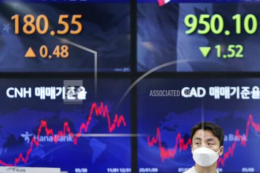 A currency trader walks near the screens showing the foreign exchange rates at a foreign exchange dealing room in Seoul, South Korea, Friday, Jan. 14, 2022. Asian shares slipped Friday after a retreat on Wall Street that left the Nasdaq composite down 2.5%.(AP Photo/Lee Jin-man)