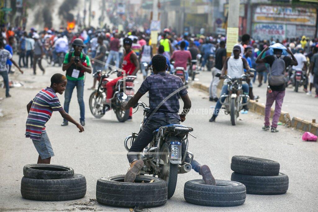 Dieu Nalio Chery A motorcyclist uses his feet to drag tires into place for a barricade during a protest to demand the resignation of President Jovenel Moise in Port-au-Prince, Haiti, Saturday, Oct. 17, 2020. The country is currently experiencing a political impasse without a parliament and is now run entirely by decree under Moise. ( AP Photo/Dieu Nalio Chery)