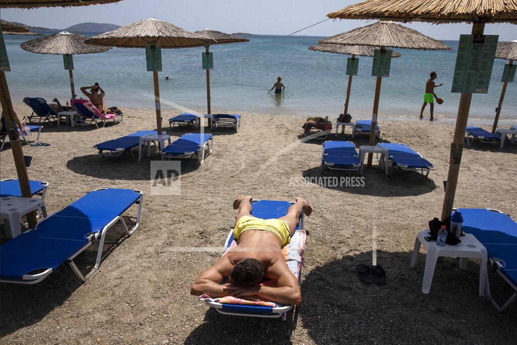 Yorgos Karahalis A man sunbathes at a beach of Lagonissi village, a few miles southwest of Athens, on Thursday, July 29, 2021. One of the most severe heat waves recorded since 1980s scorched southeast Europe on Thursday, sending residents flocking to the coast, public fountains and air-conditioned locations to find some relief, with temperatures rose above 40 C (104 F) in parts of Greece and across much of the region. (AP Photo/Yorgos Karahalis)