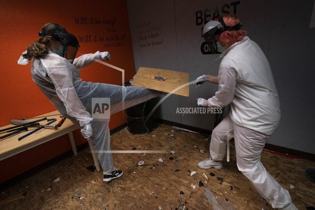 Jae C. Hong Piper Mape, 17, right, watches as her sister, Berkley, 15, kicks a wooden board in a rage room during a session to help relieve stress at Smash RX LLC in Westlake Village, Calif., Friday, Feb. 5, 2021. (AP Photo/Jae C. Hong)