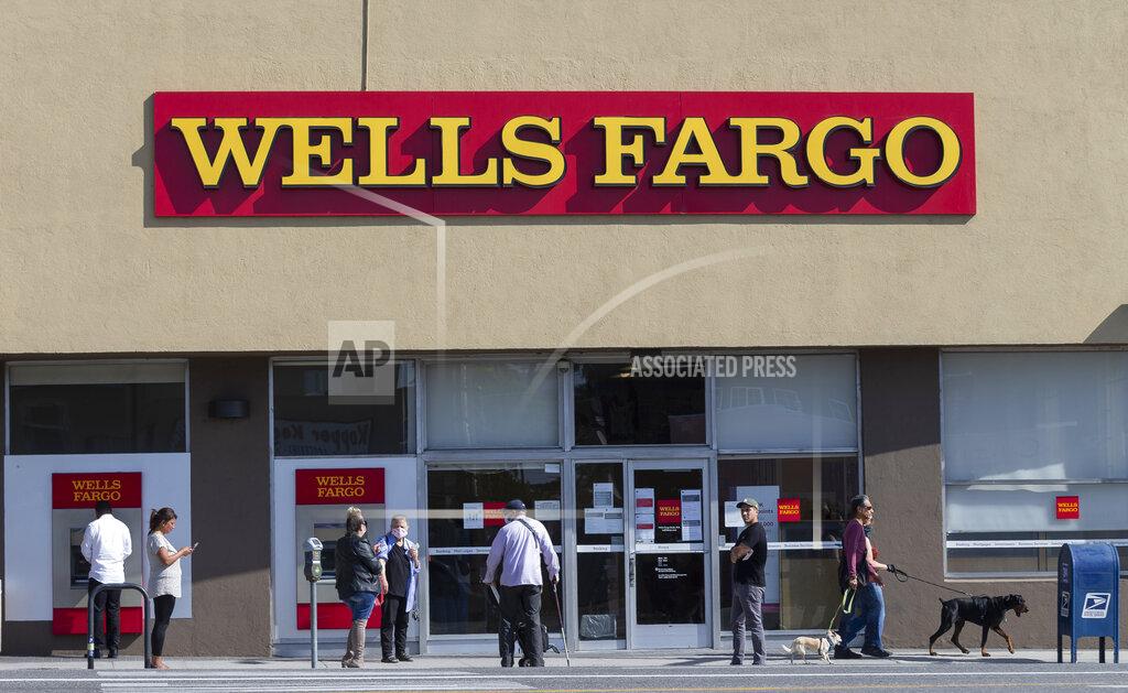 Damian Dovarganes FILE - In this April 3, 2020, file photo, customers, some wearing face masks, line up outside a Wells Fargo branch in the Atwater Village neighborhood of Los Angeles, during the coronavirus outbreak. Wells Fargo, on Tuesday, July 14, says it lost $2.4 billion in the second quarter, the first quarterly loss for the bank since the real estate crash of 2008. (AP Photo/Damian Dovarganes, File)