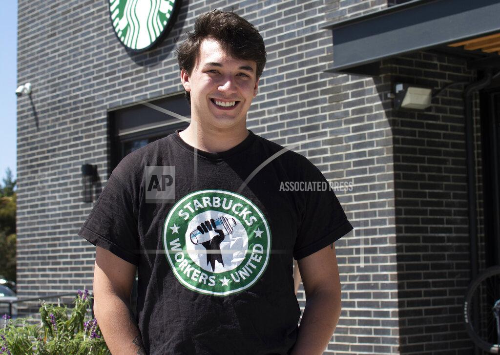 Uncredited Joe Thompson stands in front of Starbucks in Santa Cruz, Calif., on May 20, 2022. It’s become a common sight: jubilant Starbucks workers celebrating after successful votes to unionize at dozens of U.S. stores. But when the celebrations die down, a daunting hurdle remains. To win the changes they seek, like better pay and more reliable schedules, unionized stores must sit down with Starbucks and negotiate a contract. I(Joe Thompson via AP)
