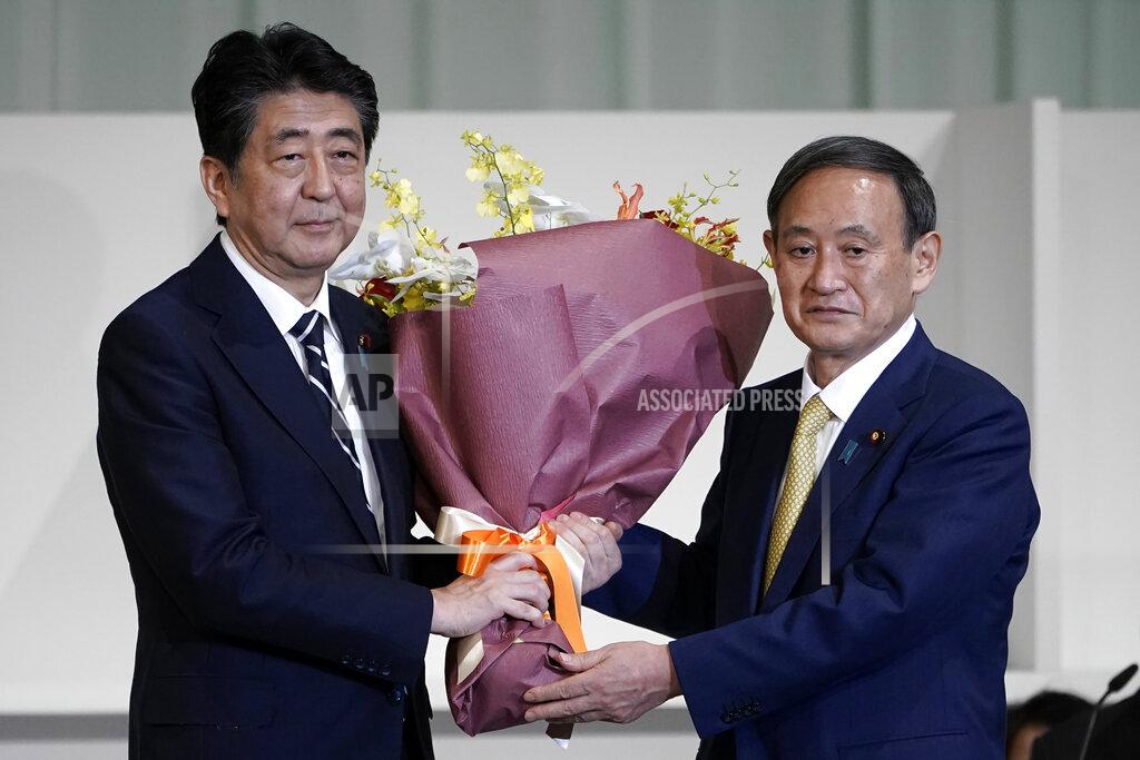 Eugene Hoshiko FILE - In this Sept. 14, 2020, file photo, Japan's then Prime Minister Shinzo Abe, left, receives flowers from then Chief Cabinet Secretary Yoshihide Suga after Suga was elected as new head of Japan's ruling party at the Liberal Democratic Party's (LDP) leadership election in Tokyo. Japan's new Prime Minister Suga heads to Vietnam and Indonesia on Sunday, Oct. 18, 2020, on his first overseas foray since taking over from his former boss Abe last month. (AP Photo/Eugene Hoshiko, Pool, File)