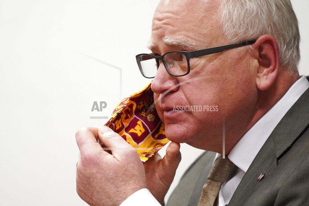 Anthony Souffle Minnesota Gov. Tim Walz takes off his University of Minnesota cloth face mask to answer a question from a reporter during a press conference for reporters not in the Twin Cities metro area to debut his state budget plan for the next two years Tuesday, Jan. 26, 2021 at the Department of Revenue building in St. Paul, Minn. (Anthony Souffle/Star Tribune via AP)