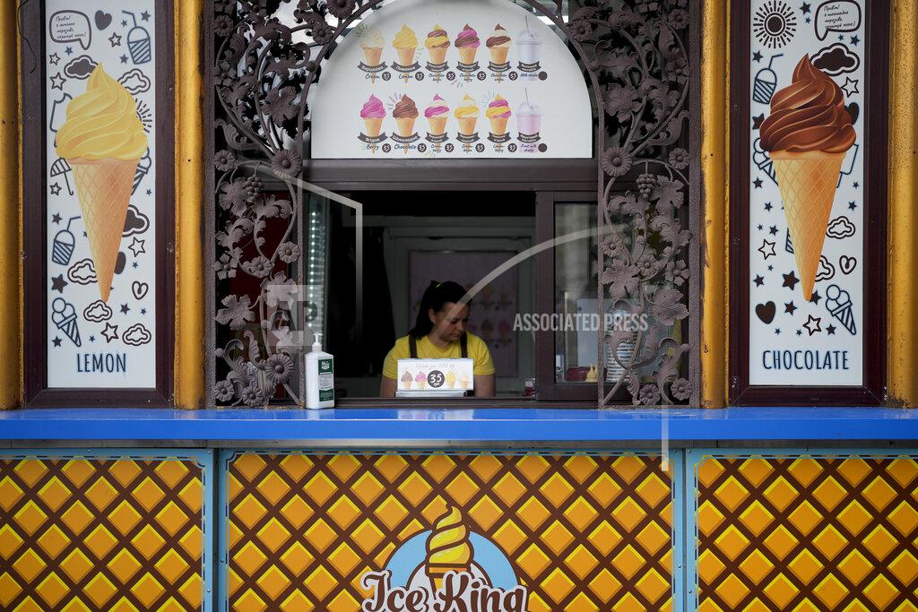 Natacha Pisarenko A woman waits for customers at an ice cream stand in Kyiv, Ukraine, Monday, May 23, 2022. Curfews, checkpoints and fortifications have become commonplace after 90 days of war in Ukraine. So have fresh cemeteries, uprooted villagers and war-scarred landscapes as Moscow intensifies its attacks in eastern and southern Ukraine. (AP Photo/Natacha Pisarenko)