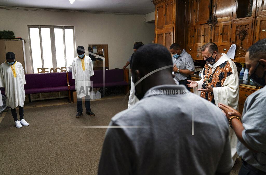 David Goldman The Rev. Michael Pfleger, second from right, leads a prayer before delivering Mass at St. Sabina Catholic Church in the Auburn Gresham neighborhood in Chicago, Sunday, Aug. 23, 2020. "Forty-five years I've been here and never has it been as bad as it is right now in terms of hopelessness, anger and despair. Never," says Pfleger, one of the city's most vocal social activists. One day in July, a gang dispute erupted in a shootout in front of a local funeral home, wounding 15 and leaving 60 bullet casings strewn about the sidewalk. Pfleger walked over to the scene, then went home and cried. (AP Photo/David Goldman)